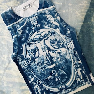 May include: A white sleeveless tank top with a blue and white print of an angel with wings and a cherub. The print is surrounded by a decorative frame and other cherubs. The tank top has the word "ZOO" printed on the front.