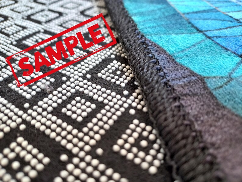 Puede incluir: Primer plano de una tela con estampado blanco y negro con un sello rojo "SAMPLE". La tela est&aacute; cosida a una tela con estampado azul y negro.