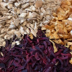 May include: A close-up of a mixture of dried herbs and spices. The mixture includes light brown ginger, orange peel, and dark red hibiscus.