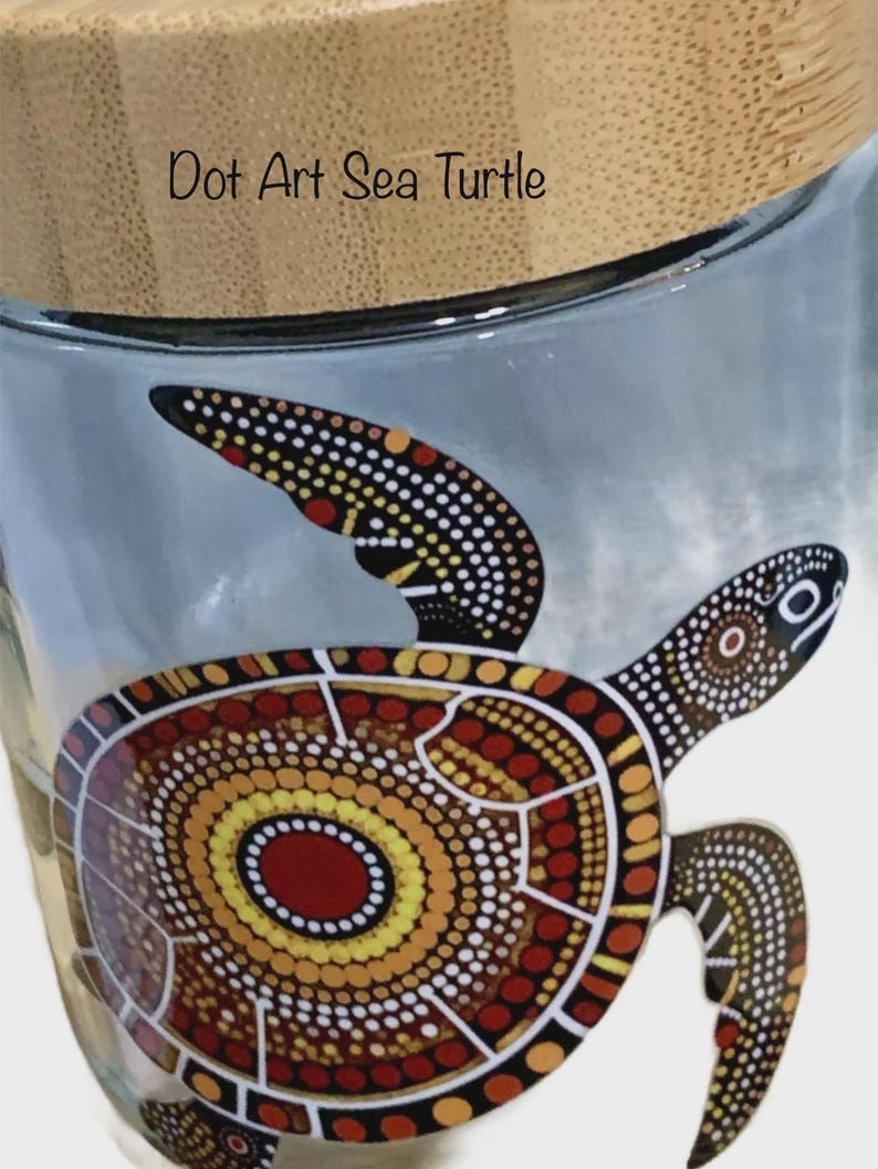 May include: A clear glass jar with a light-colored bamboo lid featuring a dot art sea turtle design in shades of red, orange, yellow, and black. The text Dot Art Sea Turtle is printed in black on the upper portion of the glass jar surface.