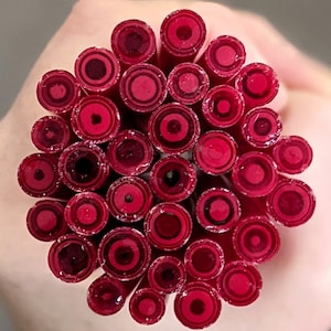 May include: A collection of red and white glass rods with a circular pattern. The rods are arranged in a circle, with the ends of the rods facing the viewer.
