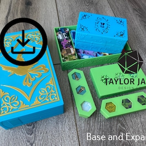 May include: A blue and green board game storage set featuring a book-shaped box with a gold phoenix emblem, a green tray containing small game pieces, and two green rectangular organisers with hexagonal cutouts. Text reads Taylor Jane Design Co.