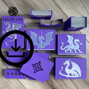 Puede incluir: Colección de cajas y accesorios morados para juegos de cartas, con diseños de dragones. Las cajas varían en tamaño y forma, algunas contienen pilas de cartas. El texto "TAYLOR JANE" es visible en una caja. También hay un dado d20 negro.