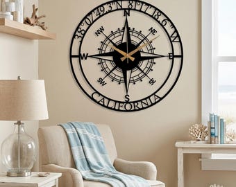 May include: A circular black metal wall clock featuring a compass rose design with cardinal directions, the text 38 07 49.3 N 81 17 18.6 W, and the word CALIFORNIA at the bottom. The clock has gold-colored hour and minute hands.