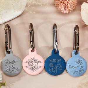 Könnte beinhalten: Vier personalisierte Haustier-ID-Tags mit verschiedenen Designs und Namen. Die Tags sind rund und aus einem weichen, flexiblen Material gefertigt. Die Namen auf den Tags sind "Buster", "Nadine", "Buddy" und "Oscar".