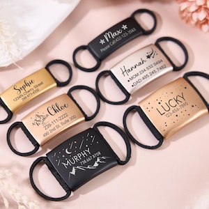 May include: Several personalised pet ID tags in gold, silver, and black are displayed. Each tag has a name and contact details, with some including decorative elements such as stars and mountain graphics. The tags have a loop for easy attachment.