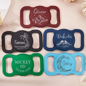 May include: A collection of five colorful pet ID tags. Each tag features a unique design and name, including "Oliver," "Simon," "Dakota," "Mickey," and "Sidney." The tags are in various colors: burgundy, black, navy blue, green, and light blue.