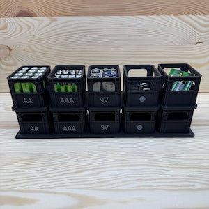 Könnte beinhalten: Ein schwarzer Batterie-Organizer mit Fächern für AA-, AAA- und 9V-Batterien. Der Organizer ist mit Batterien gefüllt und bietet eine ordentliche Aufbewahrungslösung. Die Beschriftungen sind gut sichtbar.