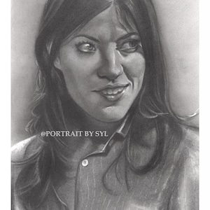May include: A grayscale pencil portrait of a woman with long hair, wearing a button-down shirt. The artwork is signed and includes the text "@PORTRAIT BY SYL". The portrait captures a subtle smile and a thoughtful gaze.