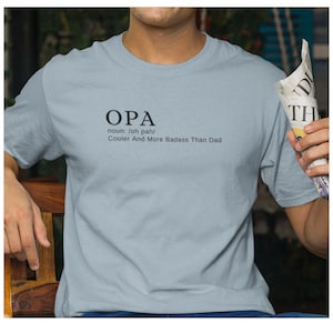 May include: A light blue t-shirt with the word "OPA" printed on the front. The word is defined as "noun: /oh pah/ Cooler And More Badass Than Dad."