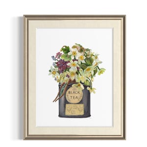 May include: Watercolor print of a black tea tin filled with white and yellow flowers and greenery. The tin has a gold label that reads "BLACK TEA". The artwork is framed in a gold-colored frame.