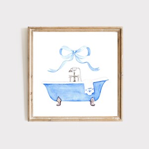 Peut inclure: Une peinture &agrave; l'aquarelle d'une baignoire bleue avec une serviette blanche et un n&oelig;ud bleu sur le dessus. La baignoire a des pieds dor&eacute;s et un robinet argent&eacute;.