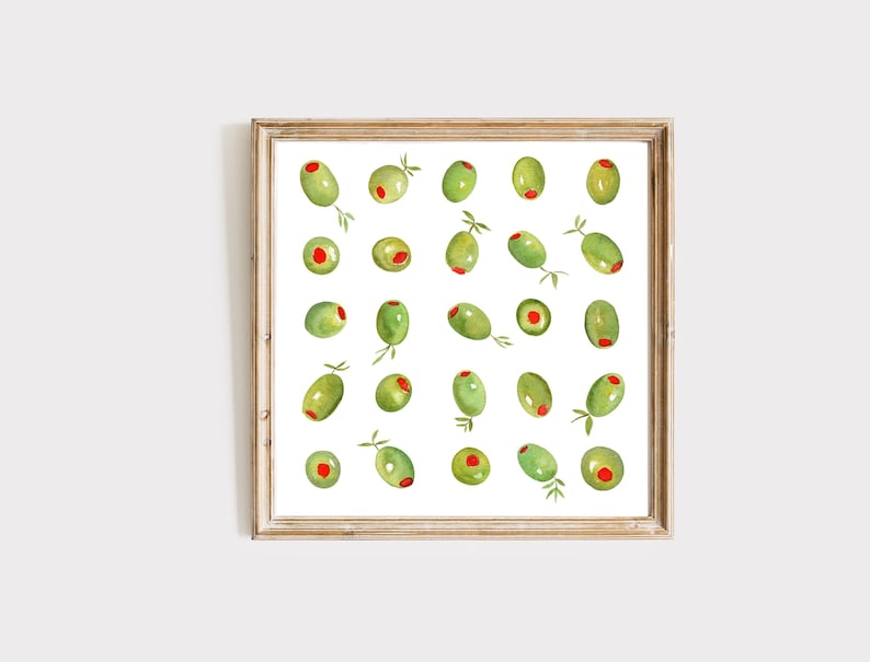 May include: Watercolor print of green olives with red pimentos, some with small sprigs, arranged on a white background. The artwork is framed in a light brown wooden frame, perfect for kitchen or dining room decor.