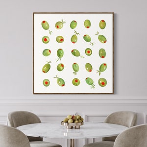 May include: A framed print featuring a watercolor illustration of green olives with red centers. The olives are arranged in a grid pattern against a white background. Some olives have small green leaves attached. The frame is a dark brown color.