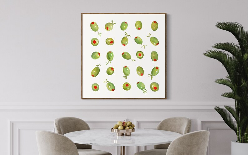 May include: A framed print featuring a watercolor illustration of green olives with red centers. The olives are arranged in a grid pattern against a white background. Some olives have small green leaves attached. The frame is a dark brown color.