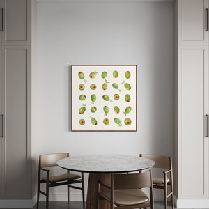 May include: A framed print featuring a watercolor illustration of green olives with red pimentos. The artwork is displayed on a white wall above a round marble-topped table with wooden chairs. The room has neutral-toned cabinets.