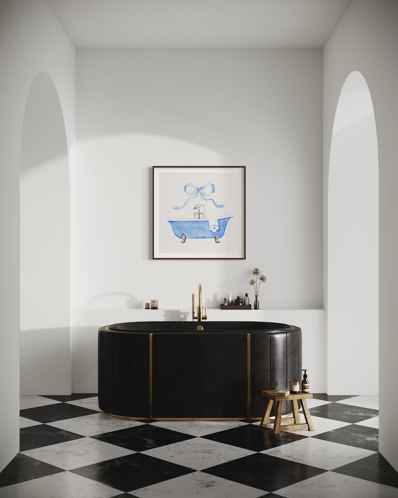 Peut inclure: Une baignoire autoportante noire avec des accents dor&eacute;s est pos&eacute;e sur un sol en damier noir et blanc. Un tableau aquarelle encadr&eacute; d'une baignoire bleue avec un n&oelig;ud bleu sur le dessus est accroch&eacute; au mur au-dessus de la baignoire.
