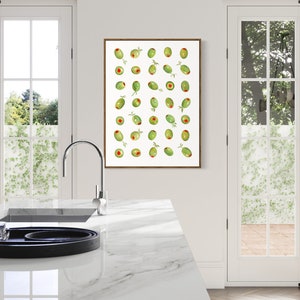 May include: A framed print featuring a pattern of green olives with red centers and small green leaves. The artwork is displayed in a bright kitchen setting with white walls, a marble countertop, and large windows.