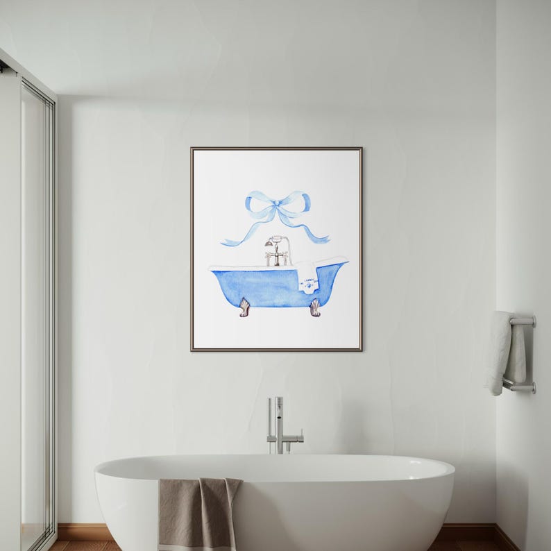May include: A framed wall art print featuring a watercolor illustration of a blue claw-foot bathtub with a silver faucet and a white towel draped over the side. A large, light blue ribbon bow is positioned directly above the bathtub illustration.