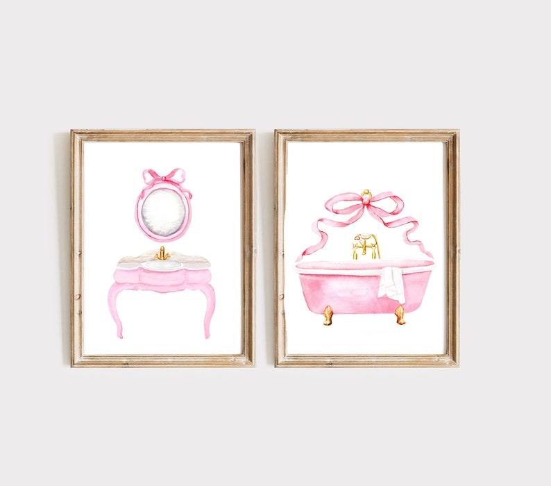May include: Two watercolor illustrations of pink bathroom fixtures with gold accents. The first image shows a vanity with a mirror and a pink ribbon. The second image shows a bathtub with a pink ribbon and a white towel.