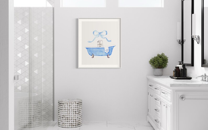 Peut inclure: Une peinture &agrave; l'aquarelle d'une baignoire bleue avec un cadeau blanc &agrave; l'int&eacute;rieur et un ruban bleu sur le dessus. La peinture est encadr&eacute;e dans un cadre blanc et est accroch&eacute;e &agrave; un mur blanc.