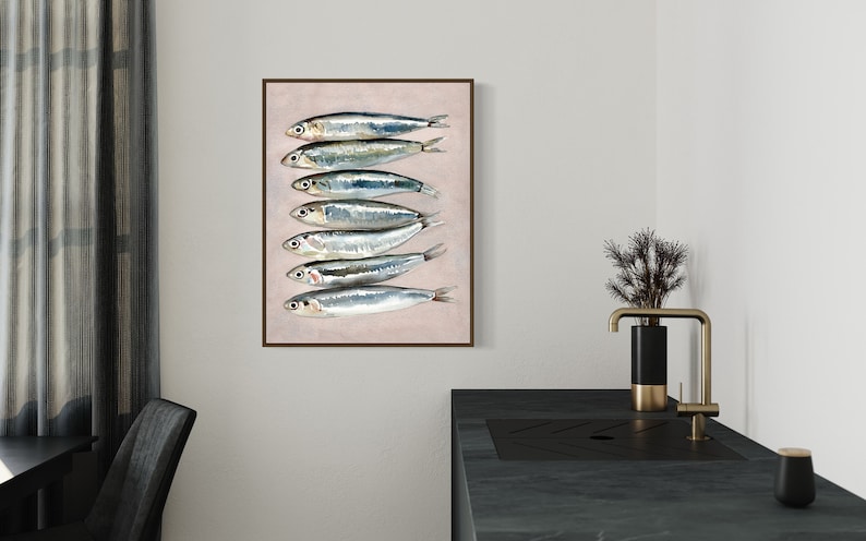 May include: A framed art print featuring a watercolor illustration of seven sardines arranged vertically. The fish have silver bodies with blue and green highlights, set against a pale pink background. The frame is a dark brown color.