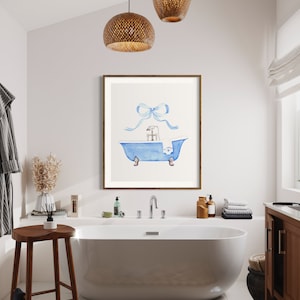 Peut inclure: Une illustration aquarelle d'une baignoire bleue avec une serviette blanche et un n&oelig;ud bleu sur le dessus. L'illustration est encadr&eacute;e et accroch&eacute;e &agrave; un mur blanc dans une salle de bain.