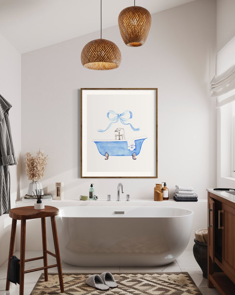 Peut inclure: Une illustration aquarelle d'une baignoire bleue avec une serviette blanche et un n&oelig;ud bleu sur le dessus. L'illustration est encadr&eacute;e et accroch&eacute;e &agrave; un mur blanc dans une salle de bain.