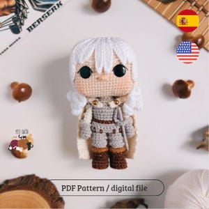 Könnte beinhalten: Handgefertigte Häkelpuppe einer Figur mit weißen Haaren, grauer Rüstung und braunen Stiefeln. Die Puppe hat große schwarze Augen und einen cremefarbenen Umhang. Der Text "PDF Pattern / digital file" ist unten im Bild zu sehen.