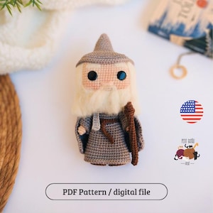 Pode incluir: Boneca de mago de crochê feita à mão com barba branca longa, chapéu cinza e cajado. A boneca tem olhos grandes e pretos e veste uma túnica cinza. A imagem inclui o texto "PDF Pattern / digital file".