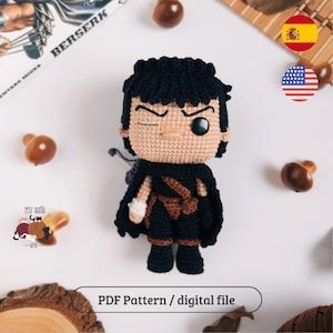 Pode incluir: Boneca de crochê de um personagem com cabelo preto, capa preta e botas pretas. A boneca tem um rosto bronzeado com um olho fechado. O texto "BERSERK" é visível no fundo. O texto "PDF Pattern / digital file" está na parte inferior.