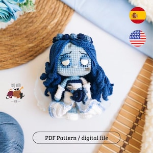 Puede incluir: Una muñeca de ganchillo hecha a mano con cabello azul y un vestido azul y blanco. La muñeca tiene una expresión triste y lleva una corona. La imagen incluye el texto "PDF Pattern / digital file".