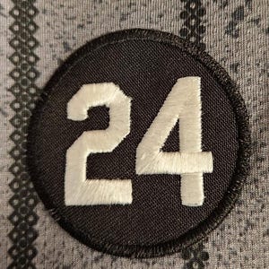 May include: A black and white circular patch with the number 24 embroidered in white on a black background.
