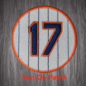 May include: A white and orange baseball-style patch with the number 17 in blue and orange. The patch is iron-on.