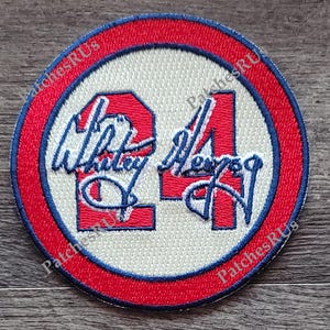 May include: A red, white, and blue embroidered patch with the number "24" and the name "Whitley" in white lettering. The patch has a blue border and a red outer ring.