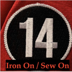 May include: White iron-on or sew-on patch with the number 14 in a black circle.