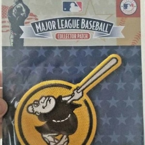 May include: A yellow and black embroidered patch featuring a cartoon baseball player holding a bat. The patch has the text "Major League Baseball" and "Collector Patch" on it.