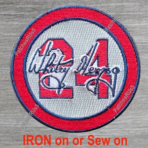 May include: A red, white, and blue embroidered patch with the number "24" and a signature. The patch is circular and has a white background with a red border and a blue outline. The text "IRON on or Sew on" is printed below the patch.