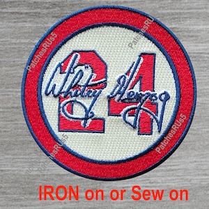 May include: A red, white, and blue embroidered patch with the number "24" and the name "Whitley" in a cursive script. The patch is circular and has a white background with a red border. The text "IRON on or Sew on" is printed below the patch.