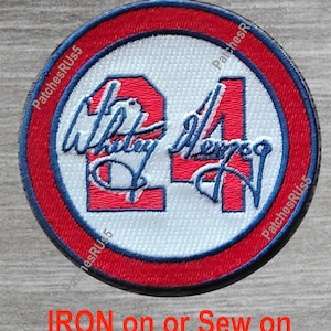 May include: A white, red, and blue embroidered patch with the number "24" and the signature "Whitley Merman" in blue thread. The patch is circular and has a red border with a blue outline. The text "IRON on or Sew on" is printed below the patch.
