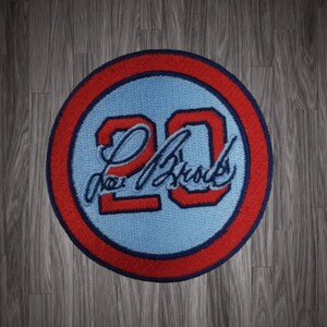May include: Red, white, and blue embroidered patch with the number 20 and the name "Lou Brock" in cursive.