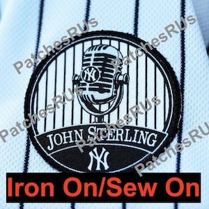 May include: A black and white patch featuring a microphone design with the New York Yankees logo. The patch includes the text "JOHN STERLING" and "Iron On/Sew On". The patch is on a pinstriped white and navy blue fabric.