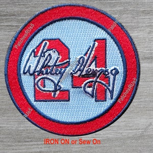 May include: A red, white, and blue embroidered patch with the number "24" and the signature "Whitley Merman" in white. The patch is circular and has a red border with a blue inner circle. The text "IRON ON or Sew On" is printed below the patch.