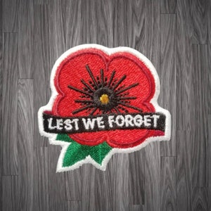 May include: Red embroidered poppy flower patch with a white border and the text "Lest We Forget" in black.