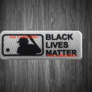 May include: A rectangular patch with the MLB logo and the words "BLACK LIVES MATTER" in black text. The patch is white with a textured surface. The words "Fun Collectibles" are also printed on the patch.