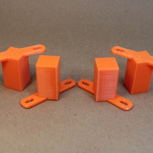 May include: Four orange 3D printed plastic blocks with two arms extending out from each side. The blocks are all the same size and shape.