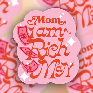 May include: Pink sticker with the text "Mom, I am a Rich Man" in red cursive lettering.  Dollar bills are falling from the top of the sticker.