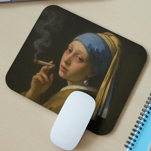 May include: A rectangular mousepad featuring a parody of Johannes Vermeer's "Girl with a Pearl Earring," with the girl holding a lit cigarette. The image has a dark background and a blue headscarf. A white computer mouse is in front of the mousepad.