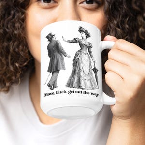 May include: A white ceramic mug featuring a black and white vintage-style illustration of a person in a top hat and a person in a Victorian dress with an umbrella. The text "Move, bitch, get out the way" is printed in black below the illustration.