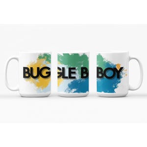 May include: Three white ceramic mugs featuring a colorful abstract watercolor design in shades of green, yellow, and blue. The text BUGLE BOY is printed in bold black capital letters across the center of the mugs, spanning the three views.